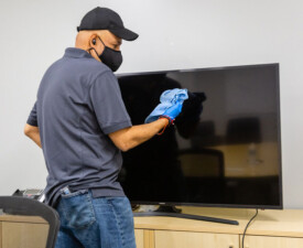 5 Star Janitorial employee dusts a TV screen