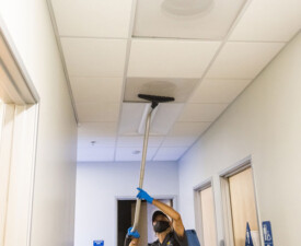 5 Star Janitorial employee vacuuming a ceiling vent