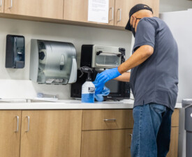 5 Star Janitorial employee cleans a kitchen appliance