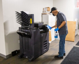 5 Star Janitorial employee wipes down an office printer
